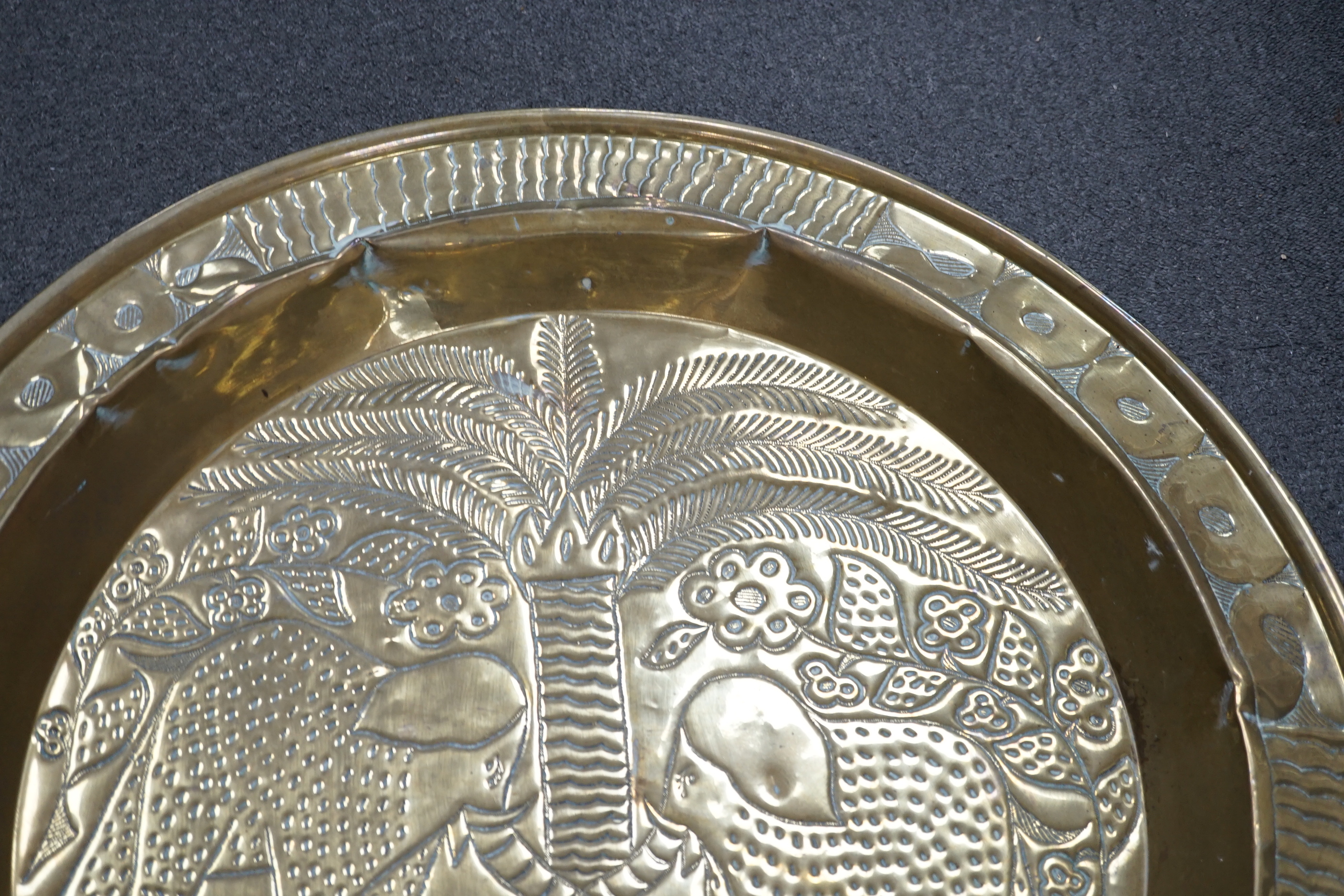 An embossed brass table top/ tray, 74cm diameter
